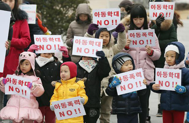 一群韩国小朋友在家长的带领下，手举“儿童暴力NO！！”的口号